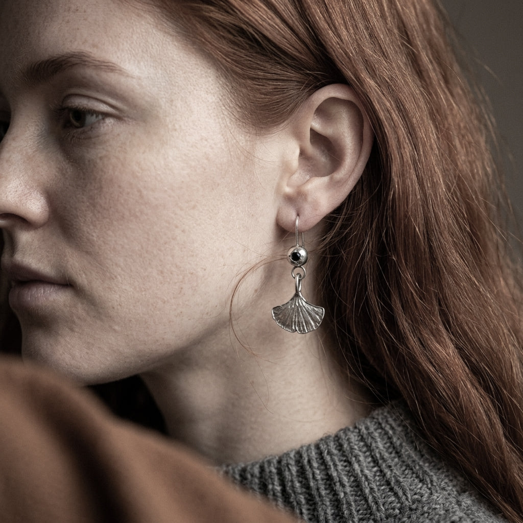 Close-up of a person wearing a silver earring with a dark background