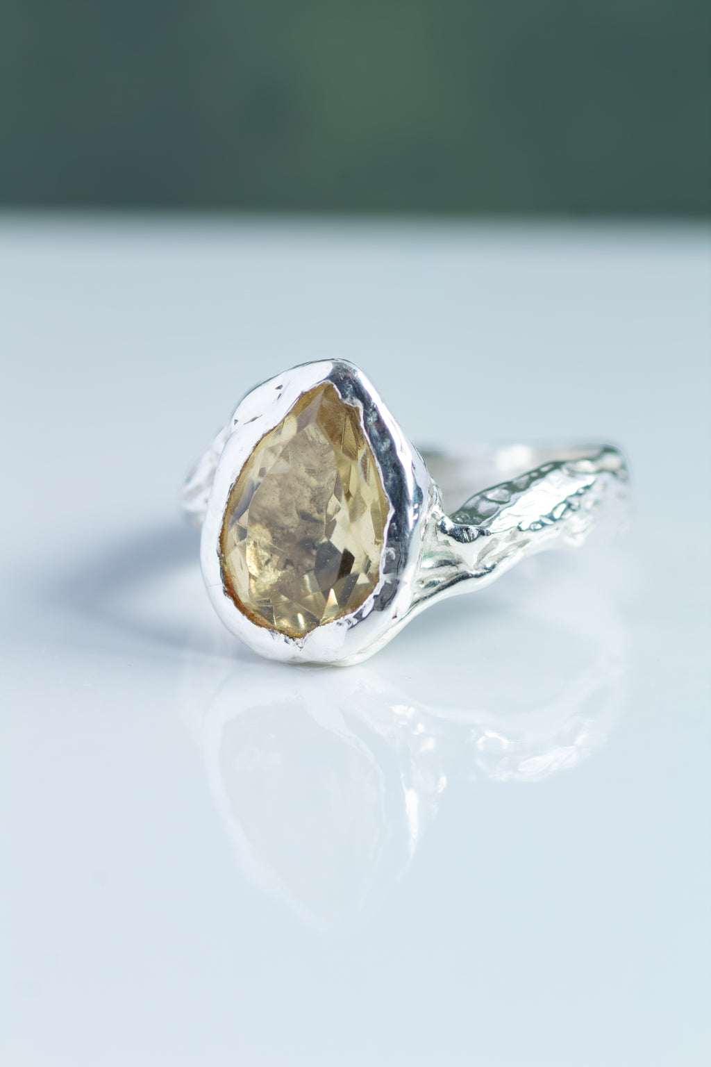 Silver ring with a yellow gemstone on a light gray background